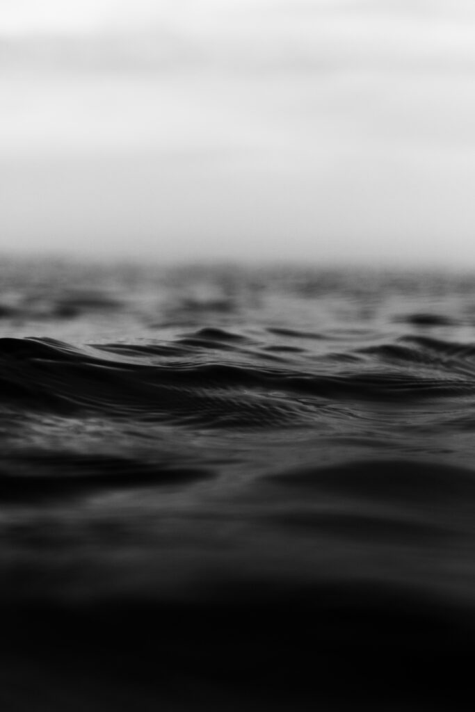 grayscale vertical shot of tiny rough sea waves